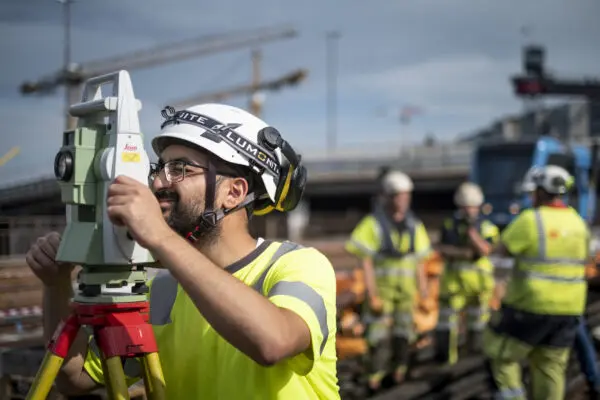 an i varselkläder och personlig skyddsutrustning utför arbete i spårmiljö för järnväg.